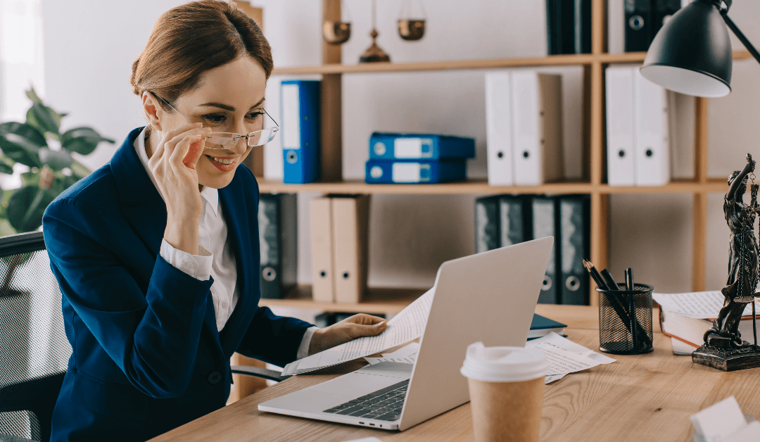 Smiling female lawyer looking at laptop screen while working at desk